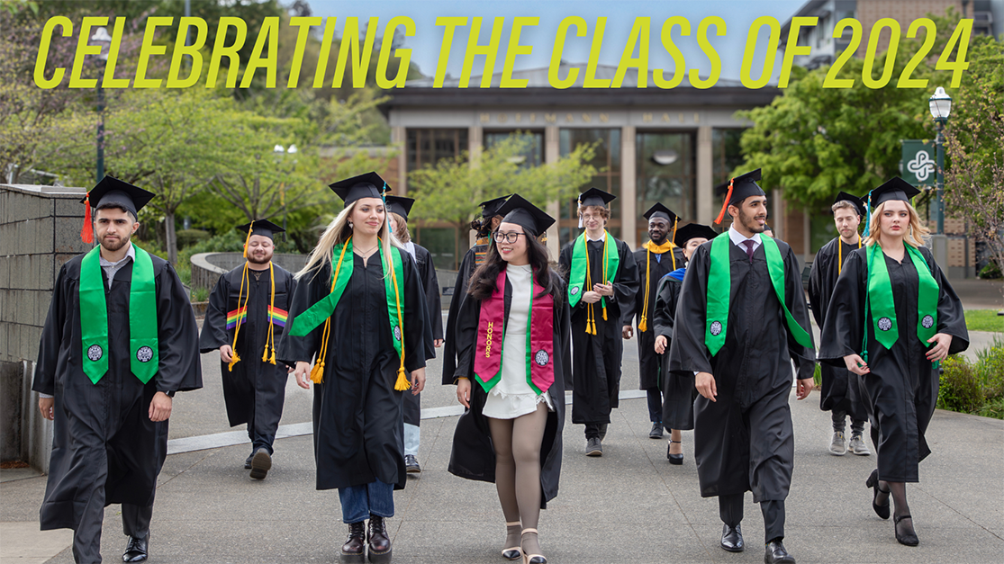 Graduates walking outside wearing regalia